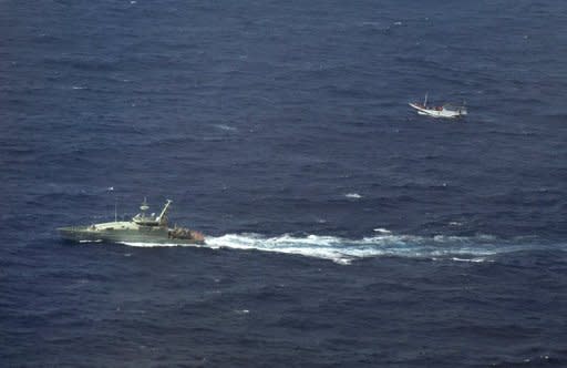 An Australian navy boat (L) shadows a boat believed to be carrying asylum-seekers and sailing towards Australian waters in July 2012. Australia is facing a steady influx of asylum-seekers arriving by boat, many of whom use Indonesia as a transit hub, paying people-smugglers for passage on leaky wooden vessels after fleeing their home countries