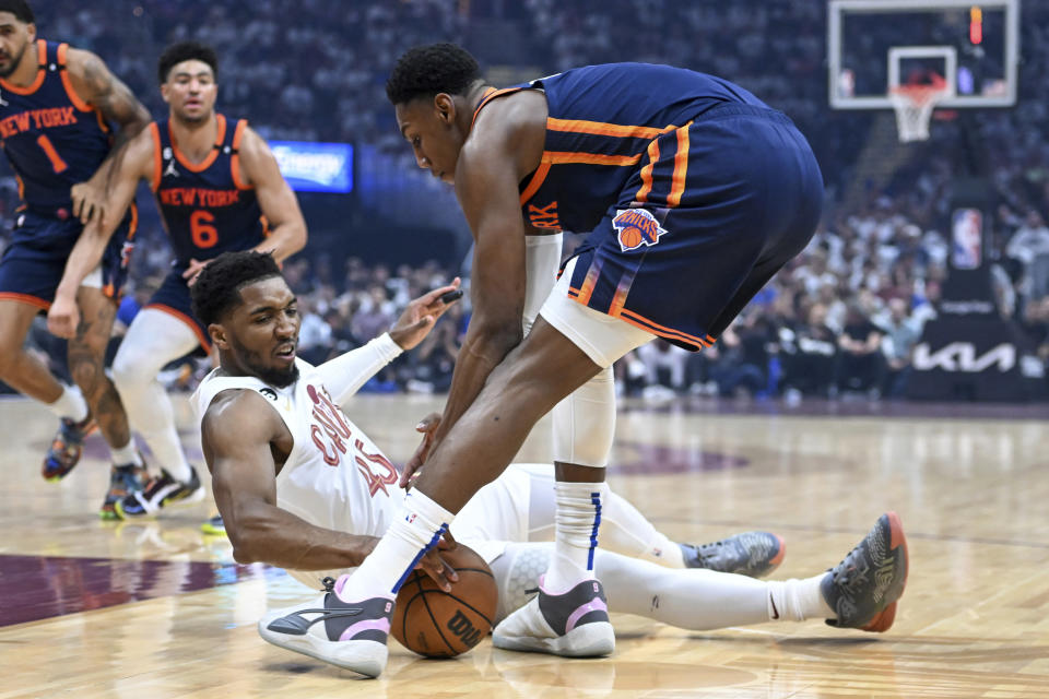Cleveland Cavaliers' Donovan Mitchell, bottom, steals the ball from New York Knicks' RJ Barrett during the first half of Game 1 in a first-round NBA basketball playoffs series Saturday, April 15, 2023, in Cleveland. (AP Photo/Nick Cammett)