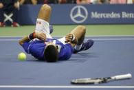 Novak Djokovic of Serbia falls to the court while trying to return a shot from Roger Federer of Switzerland in the first set during their men's singles final match at the U.S. Open Championships tennis tournament in New York, September 13, 2015. REUTERS/Mike Segar