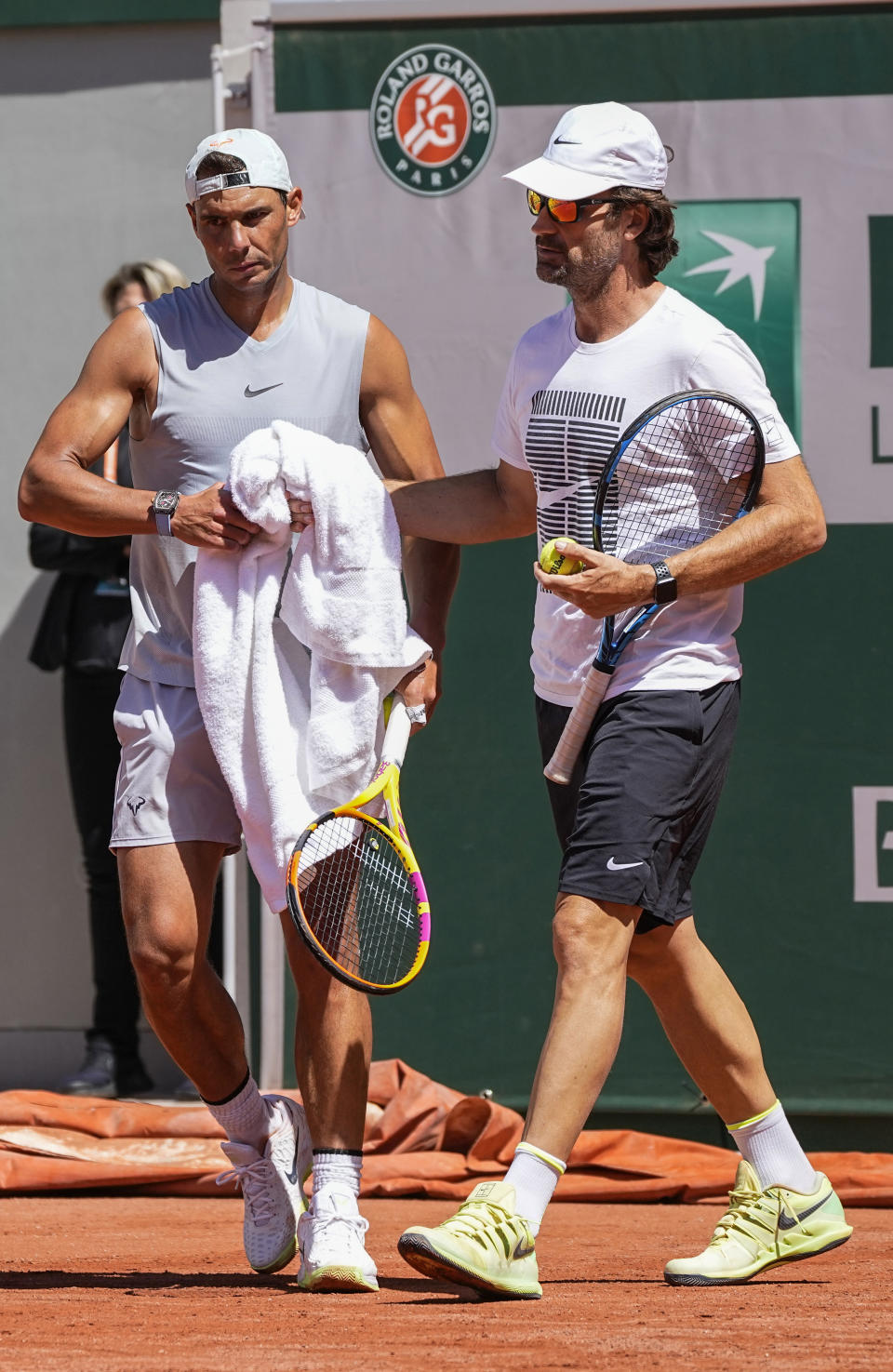 Spain's Rafael Nadal, left, takes his towel from coach Carlos Moya during a training session at Roland Garros stadium ahead of the French Open tennis tournament in Paris, Thursday, May 27, 2021. (AP Photo/Michel Euler)