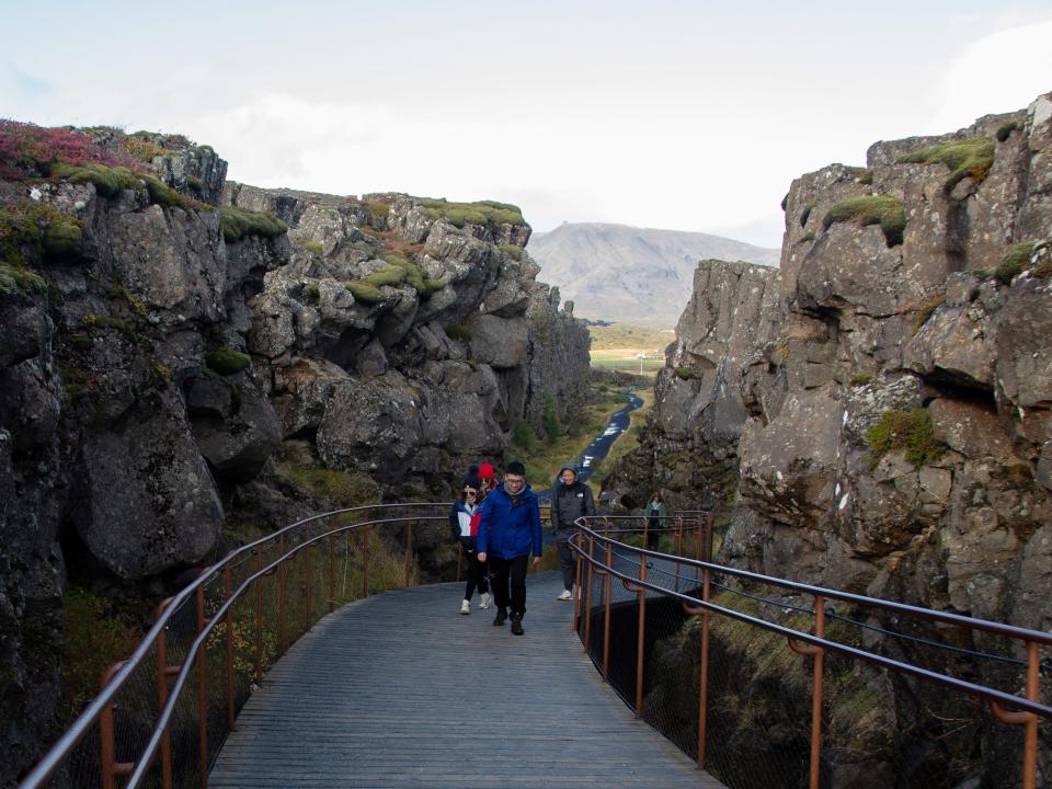 Tourists walk on a boardwalk in a Rift Valley exposing the North American and Eurasian tectonic plates, at Thingvellir National Park, Iceland