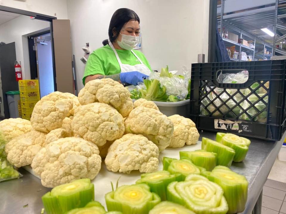 Kim Treng, a member of the Friendship Inn kitchen staff in Saskatoon, prepares vegetables for the next day&#39;s soup.  (Jason Warick/CBC - image credit)