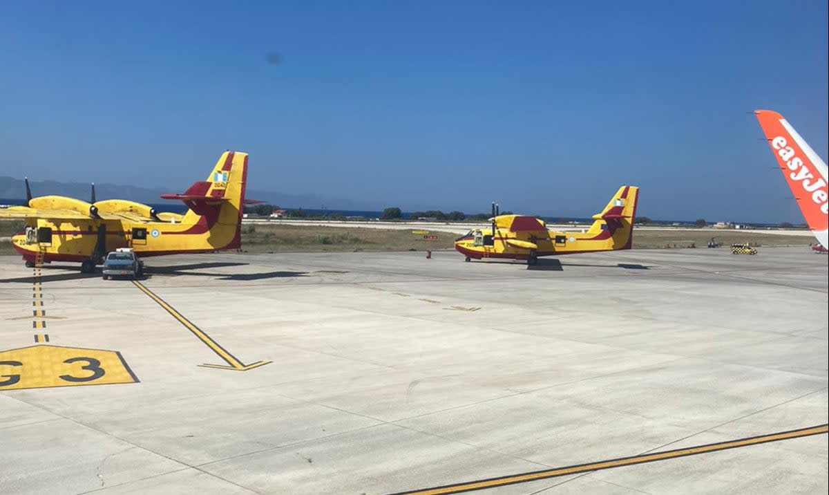 Firefighting planes sit on the tarmac as easyJet flight 8229 pulls into Rhodes airport (Andy Gregory/The Independent)