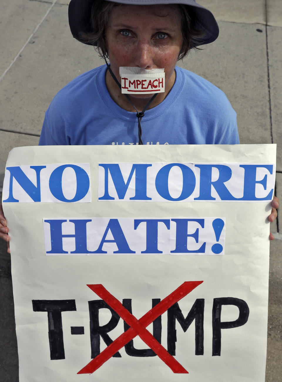 Michelle Pihos from The Villages, Fla., holds an anti President Donald Trump sign during a rally Tuesday, June 18, 2019, in Orlando, Fla. A large group of protestors were holding a rally near where Trump was announcing his re-election campaign. (AP Photo/Chris O'Meara)