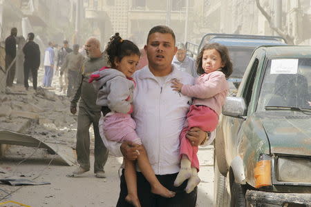 A man holds two young girls reacting as they rush out from a site hit by what activists said were barrel bombs dropped by forces of Syria's President Bashar al-Assad, at al-Thawra neighborhood in Idlib city, April 20, 2015. REUTERS/Ammar Abdullah