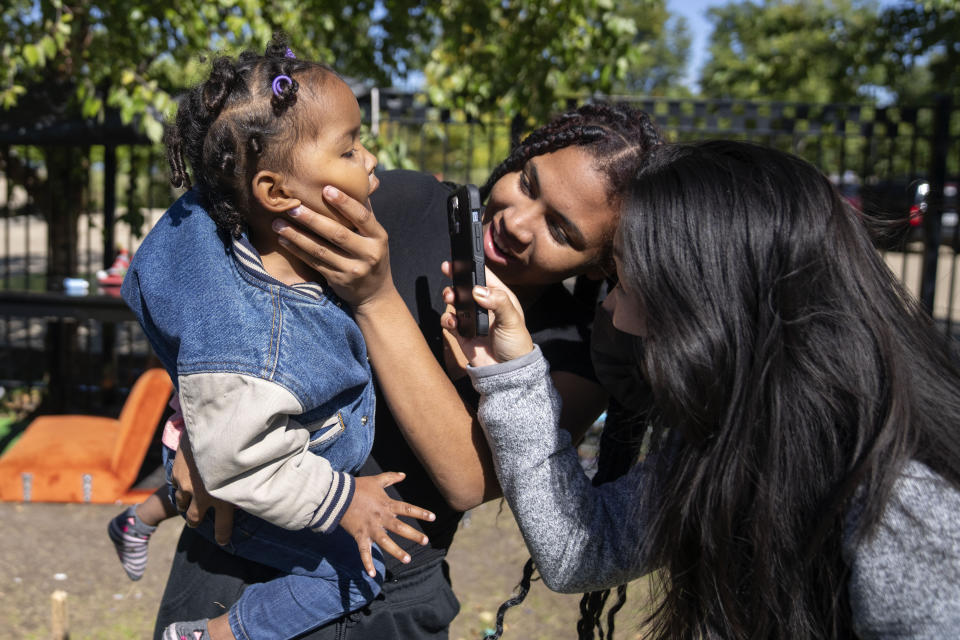 Anmani Rendon of Venezuela holds her 2-year-old daughter Sofia Barragan as med student Christina Guyn shines a light inside her mouth outside of the 12th District police station where migrants are camped, Saturday, Oct. 7, 2023, in Chicago. (AP Photo/Erin Hooley)