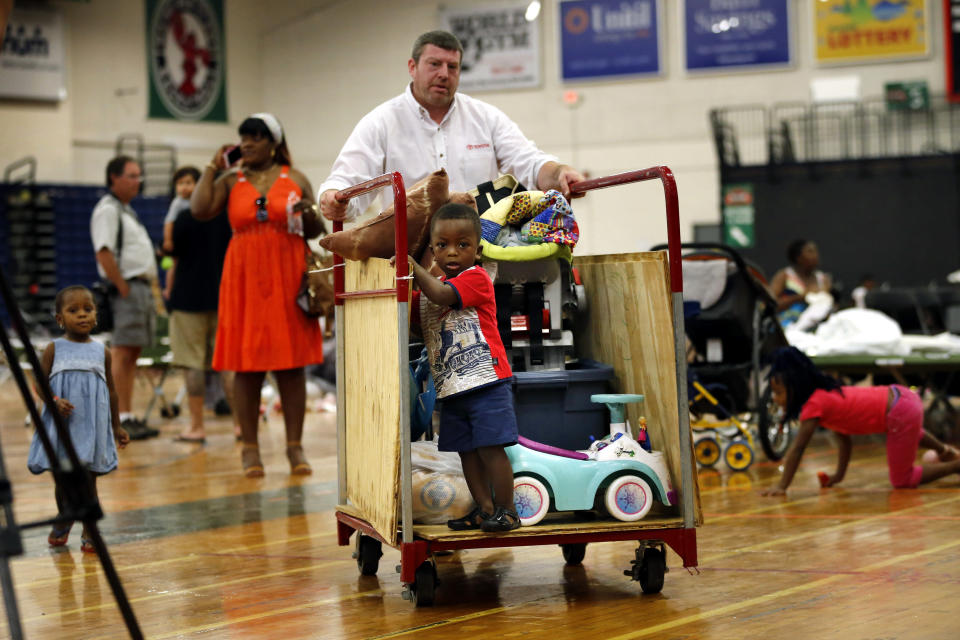 A young boy gets a ride on a luggage cart as Steve Miller helps move the belongings of African asylum seekers at the Portland Expo, Thursday, Aug. 15, 2019, in Portland, Maine. The state's largest city is racing to find homes for dozens of African asylum seekers as a temporary shelter closes on Thursday. (AP Photo/Robert F. Bukaty)