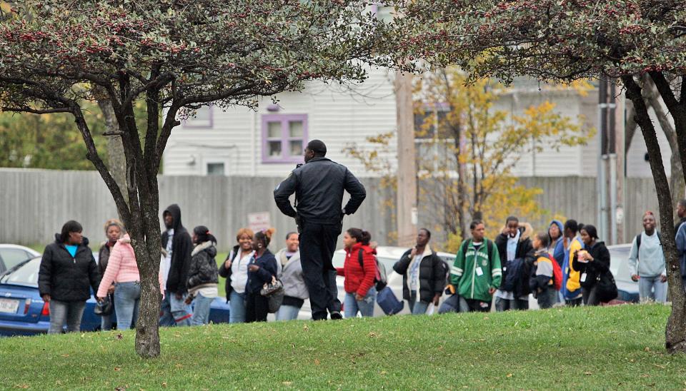 A Milwaukee police officer watches as students depart after school at North Division High School in 2006.