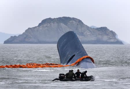 A vessel involved in salvage operations passes near the upturned South Korean ferry "Sewol" in the sea off Jindo April 17, 2014. REUTERS/Kim Kyung-Hoon