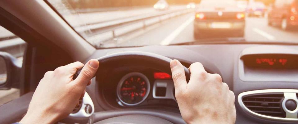 close up of driver's hands on the wheel, driving on the highway