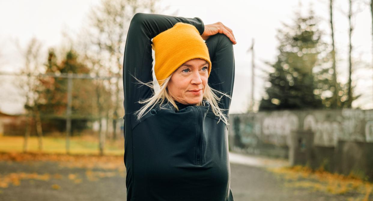 Woman in a beanie stretches before doing exercise. (Getty Images)