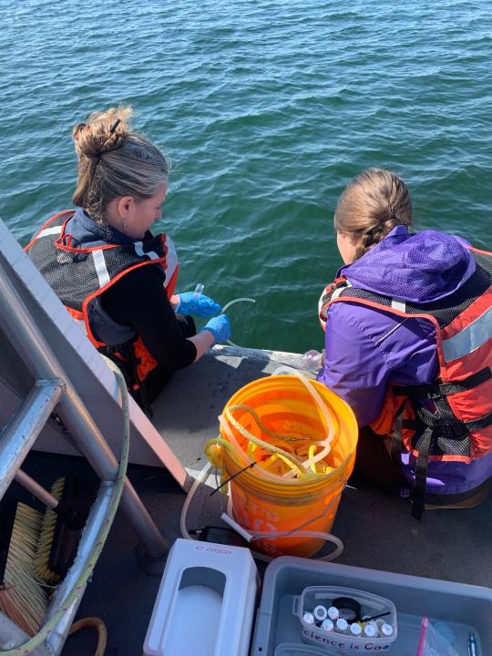 In this photo provided by the Thunder Bay National Marine Sanctuary, National Oceanic and Atmospheric Administration scientist Stephanie Gandulla, left, and Michigan Sea Grant intern Cassidy Beach collect Lake Huron water samples from a research vessel on June 3, 2022, near Alpena, Mich. They are working on a multi-year project at Thunder Bay Marine Sanctuary to determine whether the lake is becoming more acidic. (Thunder Bay National Marine Sanctuary/NOAA via AP)