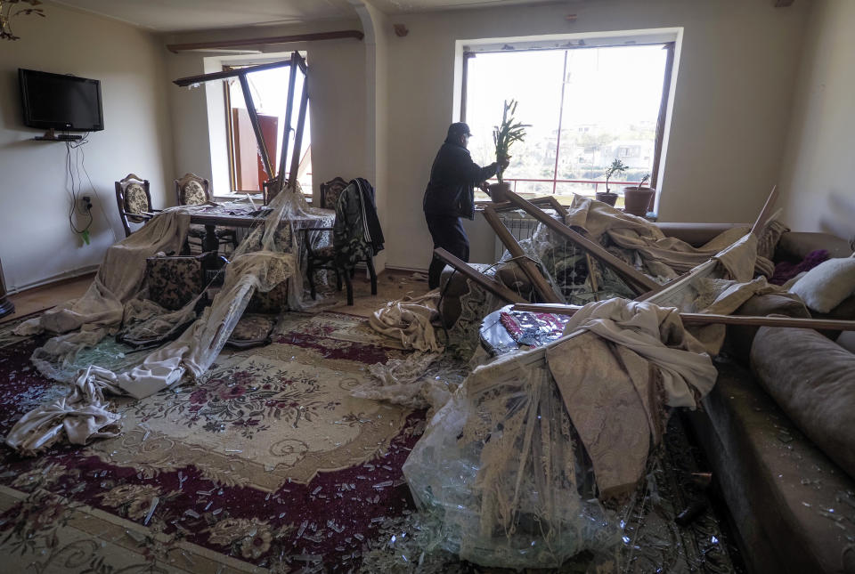 Vovik Zakharian, 72, returns a fallen flower pot to the windowsill in his apartment damaged by shelling by Azerbaijan's forces during a military conflict in Shushi, outside Stepanakert, the separatist region of Nagorno-Karabakh, Thursday, Oct. 29, 2020. Fighting over the separatist territory of Nagorno-Karabakh continued on Thursday, as the latest cease-fire agreement brokered by the U.S. failed to halt the flare-up of a decades-old conflict between Armenia and Azerbaijan. (AP Photo)