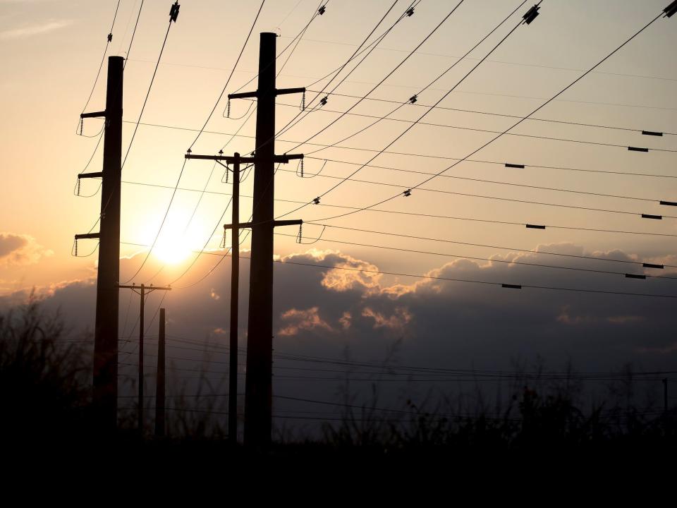 sun sets behind power transmission lines