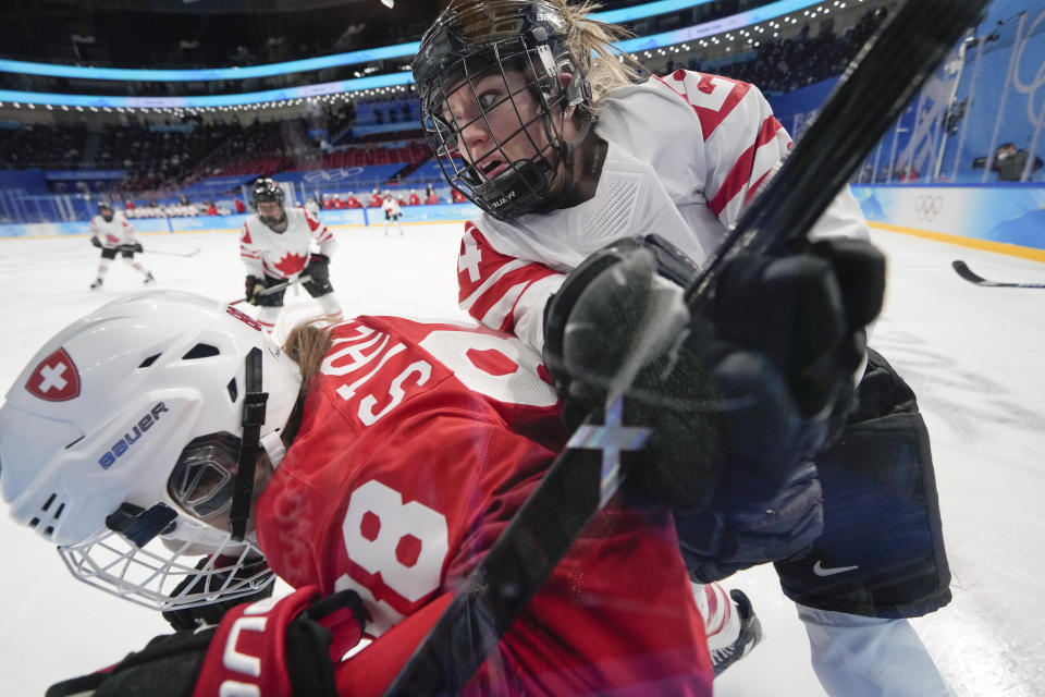 Canada's Natalie Spooner (24) checks Switzerland's Phoebe Staenz (88) against the boards during a women's semifinal hockey game at the 2022 Winter Olympics, Monday, Feb. 14, 2022, in Beijing. (AP Photo/Petr David Josek)