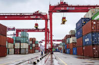 A worker walks past cranes at the container port in Qingdao in eastern China's Shandong province on Tuesday, Jan. 14, 2020. China's exports rose 0.5% in 2019 despite a tariff war with Washington after growth rebounded in December on stronger demand from other markets. (Chinatopix Via AP)