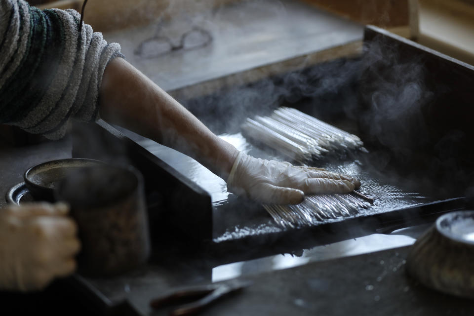 In this picture taken on Wednesday, Nov. 28, 2018, a traditional worker makes small blown glass beads for Christmas decorations in the village of Ponikla, Czech Republic. The small family business in a mountainous village in northern Czech Republic is the last place in the world where traditional Christmas decorations are made from glass beads blown and painted by hand. (AP Photo/Petr David Josek)