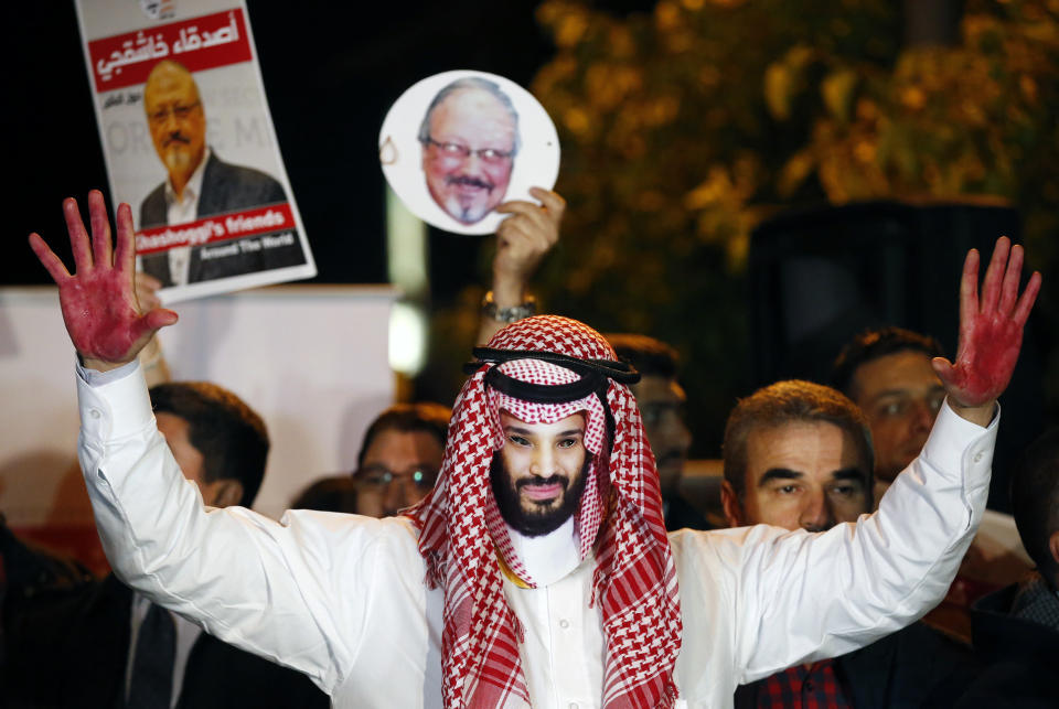 An activist wearing a mask depicting Saudi Crown Prince Mohammed bin Salman, holds up his hands painted with fake blood during a candlelight vigil for Saudi journalist Jamal Khashoggi outside Saudi Arabia's consulate in Istanbul, Thursday, Oct. 25, 2018. A group of Arab and international public, political and media figures are establishing a global association called "Khashoggi's Friends Around the World"; "to achieve justice for the freedom martyr".(AP Photo/Lefteris Pitarakis)