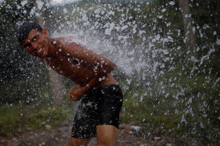 A migrant, part of a caravan of thousands traveling from Central America en route to the United States, takes a shower in Santiago Niltepec, Mexico, October 29, 2018. REUTERS/Ueslei Marcelino