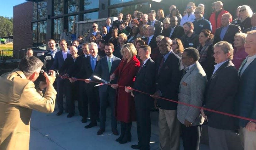 Athens Tech President Andrea Daniel cuts ribbon with scissors as Athens photographer Dennis McDaniel, left, documents the 'milestone' occasion Friday.