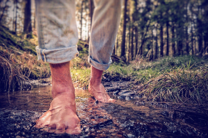 Image of man walking barefoot in a tiny pool of water and dirt