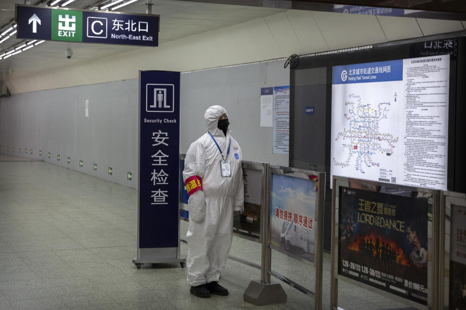 A worker wearing a hazardous materials suit stands at the entrance to a subway station in Beijing, Sunday, Jan. 26, 2020. The new virus accelerated its spread in China, and the U.S. Consulate in the epicenter of the outbreak, the central city of Wuhan, announced Sunday it will evacuate its personnel and some private citizens aboard a charter flight. (AP Photo/Mark Schiefelbein)