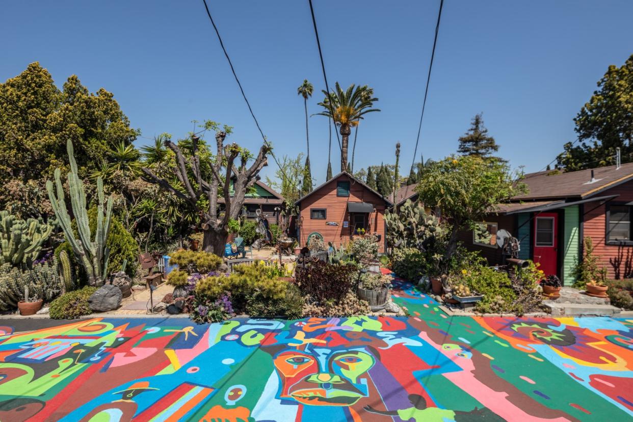 Photo of a house surrounded by trees with a colorful patio area.