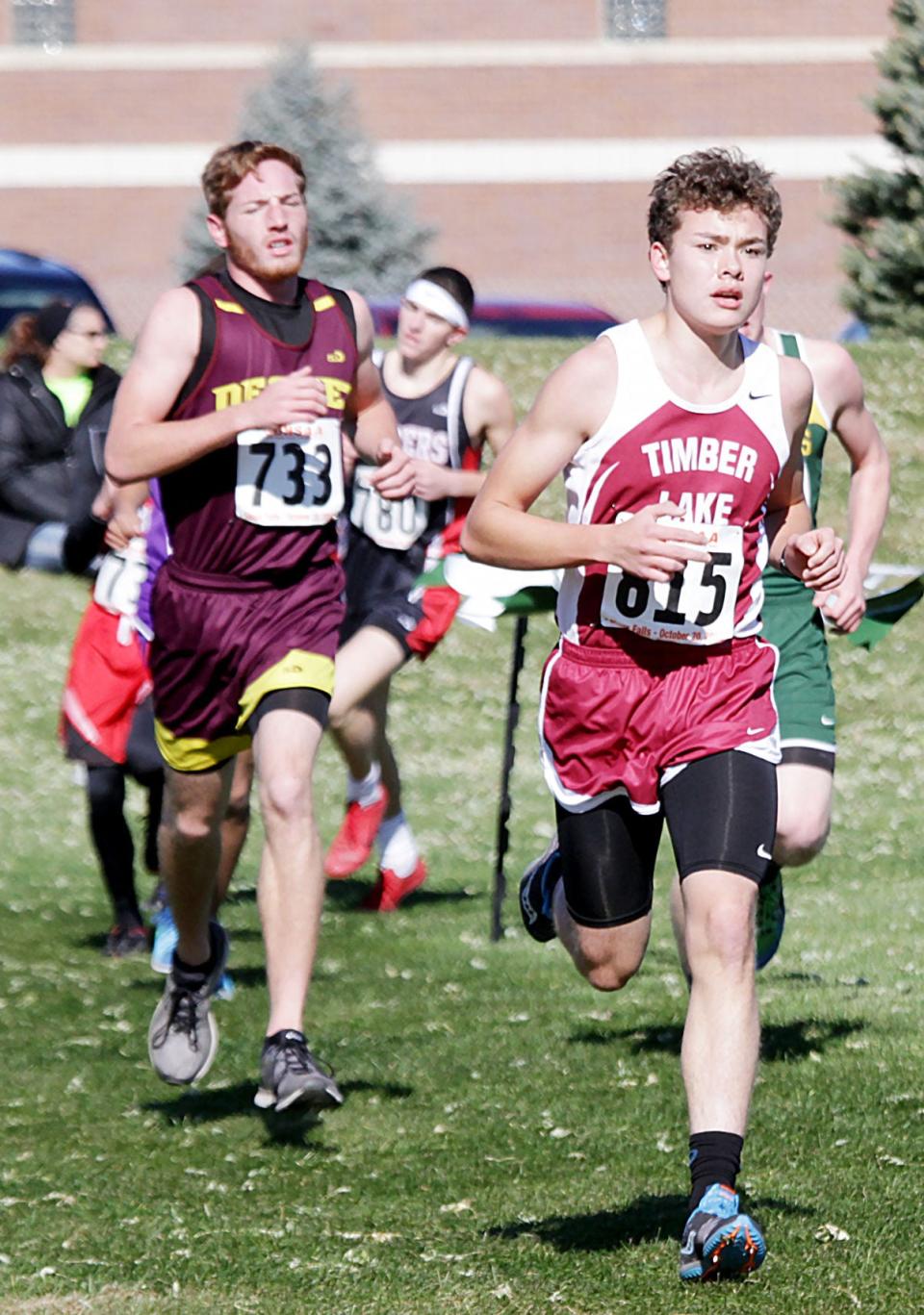 Baylor Beck of De Smet (733), shown chasing Beau DuBray of Timber Lake, was the highest area finisher in the Class B boys' race in the 2018 State High School Cross Country Meet at Sioux Falls. Beck finished 13th.