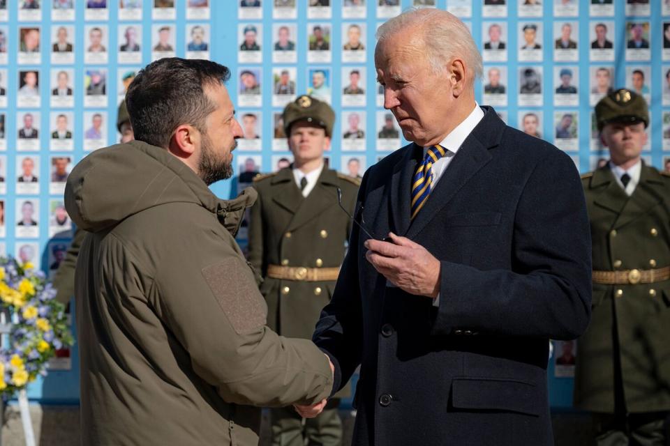 A handout photo made available by the Ukrainian Presidential Press Service on 20 February 2023 shows Ukrainian President Volodymyr Zelensky (L) and US President Joe Biden (R) attending a wreath laying ceremony at the Wall of Remembrance