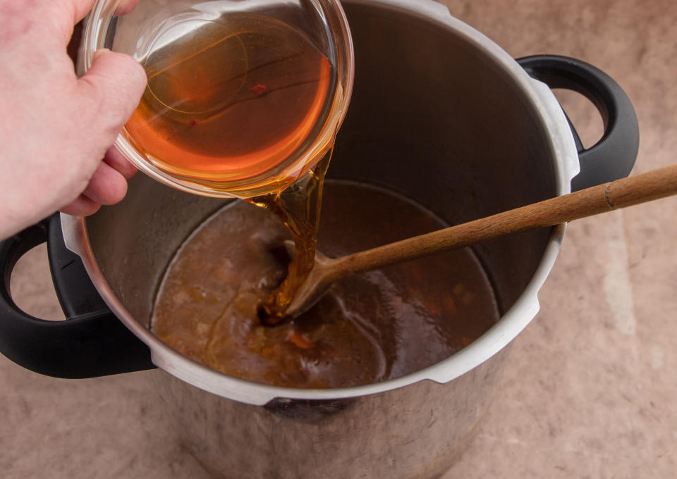 Pouring apple cider vinegar in pressure cooked beef gravy.