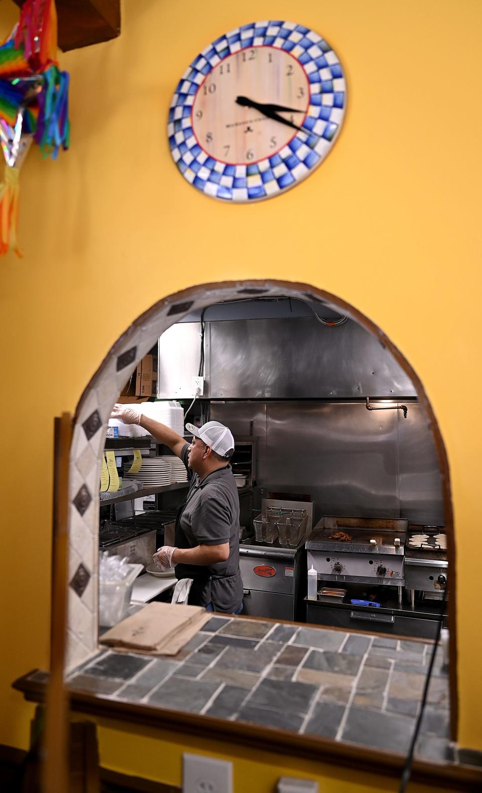 Gustavo Corona is framed by the kitchen window as he prepares a meal at Casa Del Taco Mexican Restaurant in Framingham, July 20, 2022.  