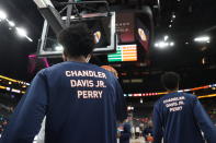 Members of the Virginia basketball team warm up Friday, Nov. 18, 2022, in Las Vegas for an NCAA college basketball game against Baylor, while wearing shirts in memory of the three students killed in a shooting nearly a week ago. (AP Photo/Chase Stevens)