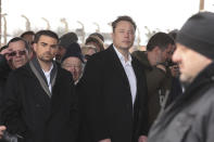 Tesla and SpaceX's CEO Elon Musk, centre, walks during his visit to the site of the Auschwitz-Birkenau Nazi German death camp in Oswiecim, Poland, on Monday, Jan. 22, 2024. The private visit was apparently in response to calls from some Jewish religious leaders for Musk to see with his own eyes the most symbolic site of the horrors of the Holocaust. (AP Photo/Andrzej Rudiak)