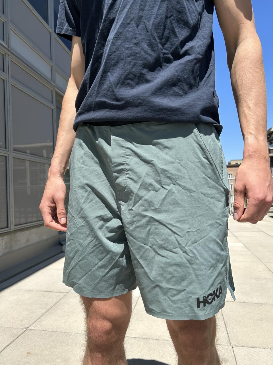 man wearing navy blue shirt and light green hoka running shorts