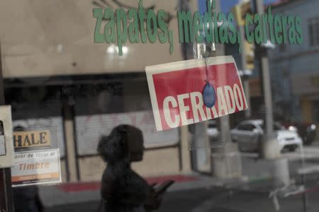 A woman walks past a shut store in San Juan, Puerto Rico, December 9, 2016. REUTERS/Alvin Baez