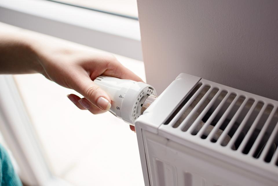 Closeup on woman's hand adjusting thermostat valve