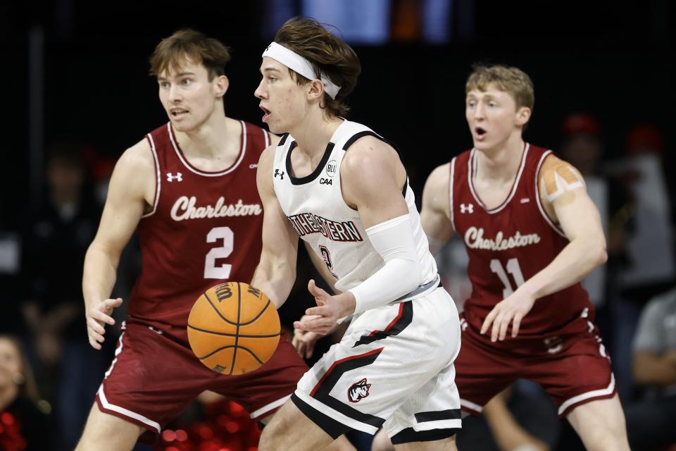 Northeastern's Glen McClintock, center, drives past Charleston's Reyne Smith (2) during the first half of an NCAA college basketball game, Saturday, Jan. 21, 2023, in Boston. (AP Photo/Michael Dwyer)