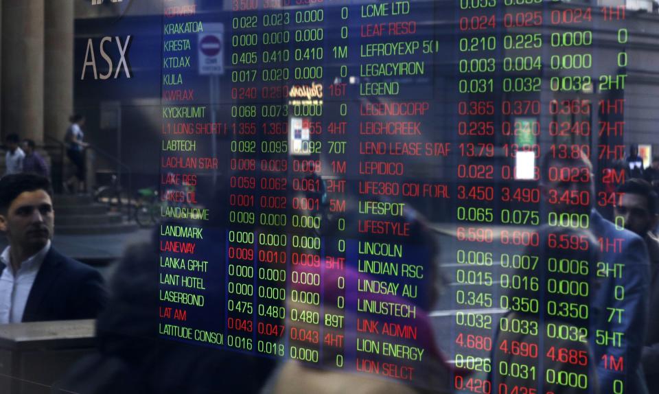 People are reflected in a window as they walk past the Australian Stock Exchange in Sydney, Thursday, Aug. 15, 2019. Asian stock markets followed Wall Street lower on Thursday after the Dow Jones Industrial Average plunged on mounting fears of a possible recession. (AP Photo/Rick Rycroft)