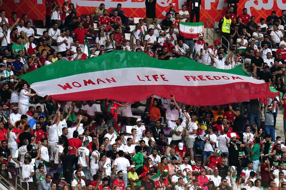 Iran fans in the stands hold up an Iran flag reading “Woman Life Freedom” during the match (PA)