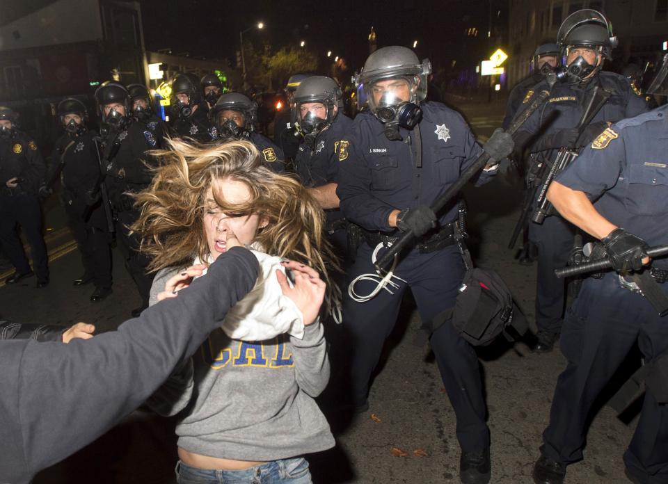 A protester flees as police officers try to disperse a crowd comprised largely of student demonstrators during a protest against police violence in the U.S., in Berkeley