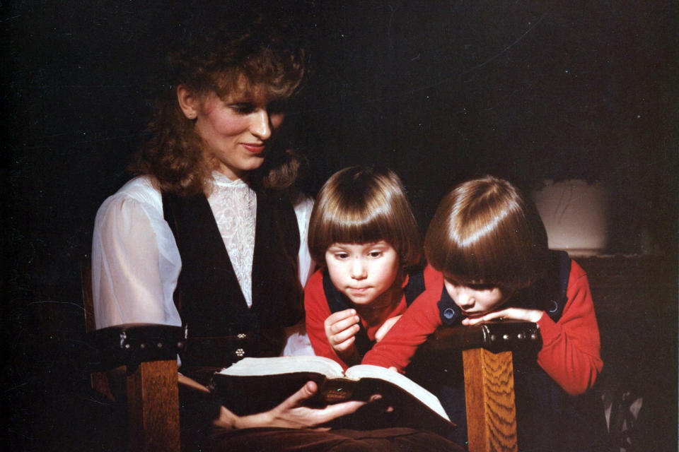 This image provided by Coral Theill, shows Theill with her twin girls in 1984, reading from their family Bible. (Coral Theill via AP)