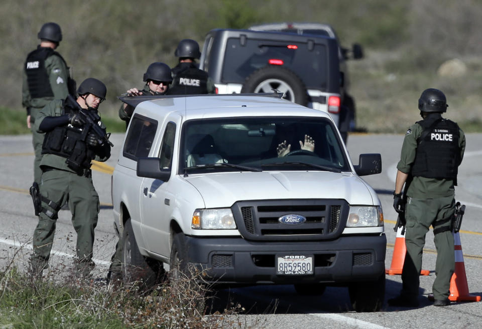 FILE - In this Tuesday, Feb. 12, 2013, file photo, Law Enforcement personnel search a vehicle along Hwy 38 during the hunt for accused killer and ex-Los Angeles police officer Christopher Dorner in Yacaipa, Caif. Eight Los Angeles police officers who mistakenly riddled a pickup truck with bullets during a manhunt for cop-turned-killer Christopher Dorner last year will be allowed to return to the field after they get additional training, Police Chief Charlie Beck said. (AP Photo/Chris Carlson, File)