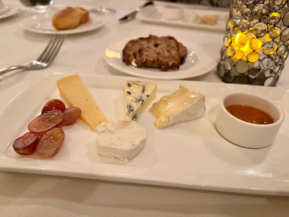 Cheese platter with a variety of cheeses and fig jam, honey, and walnut bread.