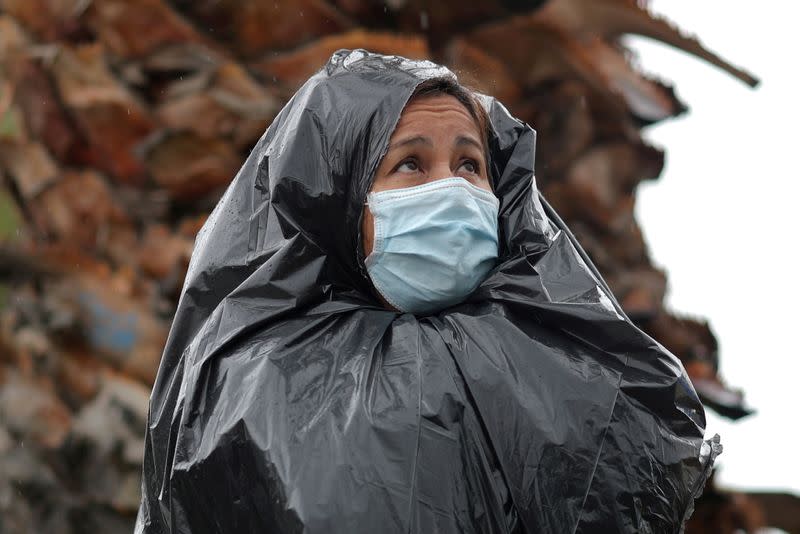 FILE PHOTO: Juana Gomez stands in the rain in a line to pick up fresh food at a Los Angeles Regional Food Bank giveaway in Los Angeles