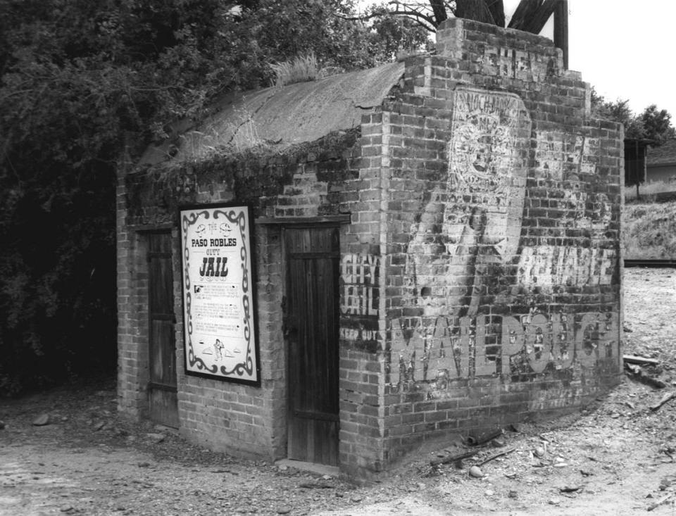 Paso Robles City Jail built in 1889 and replaced 25 years later in 1914. A Mail Pouch Tobacco ad and soap ad is painted on the side. This photo was made in 1964.