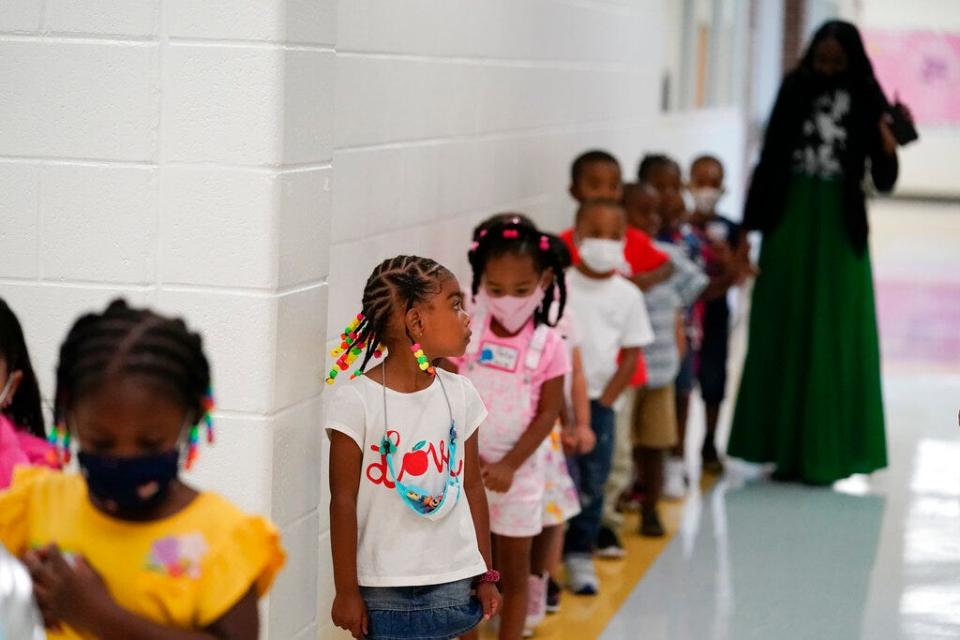FILE - Students walk down the hallway at Tussahaw Elementary school on Wednesday, Aug. 4, 2021, in McDonough, Ga., with some in masks and some unmasked. Gov. Brian Kemp on Wednesday, Feb. 9, 2022, said he would propose a law that would let parents opt their students out of masks in Georgia school districts that require them for all students to prevent the spread of COVID-19.