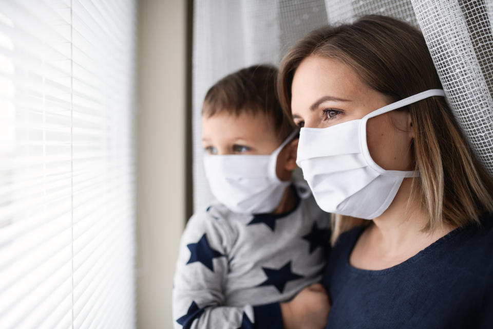 Young woman with small boy standing by window, prevention and protection.