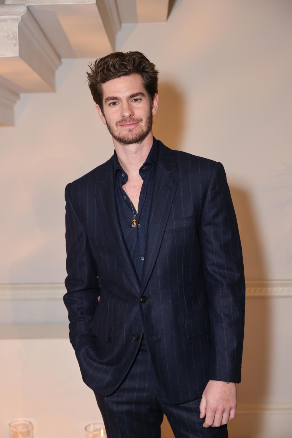 Man in pinstripe suit standing with hands in pockets