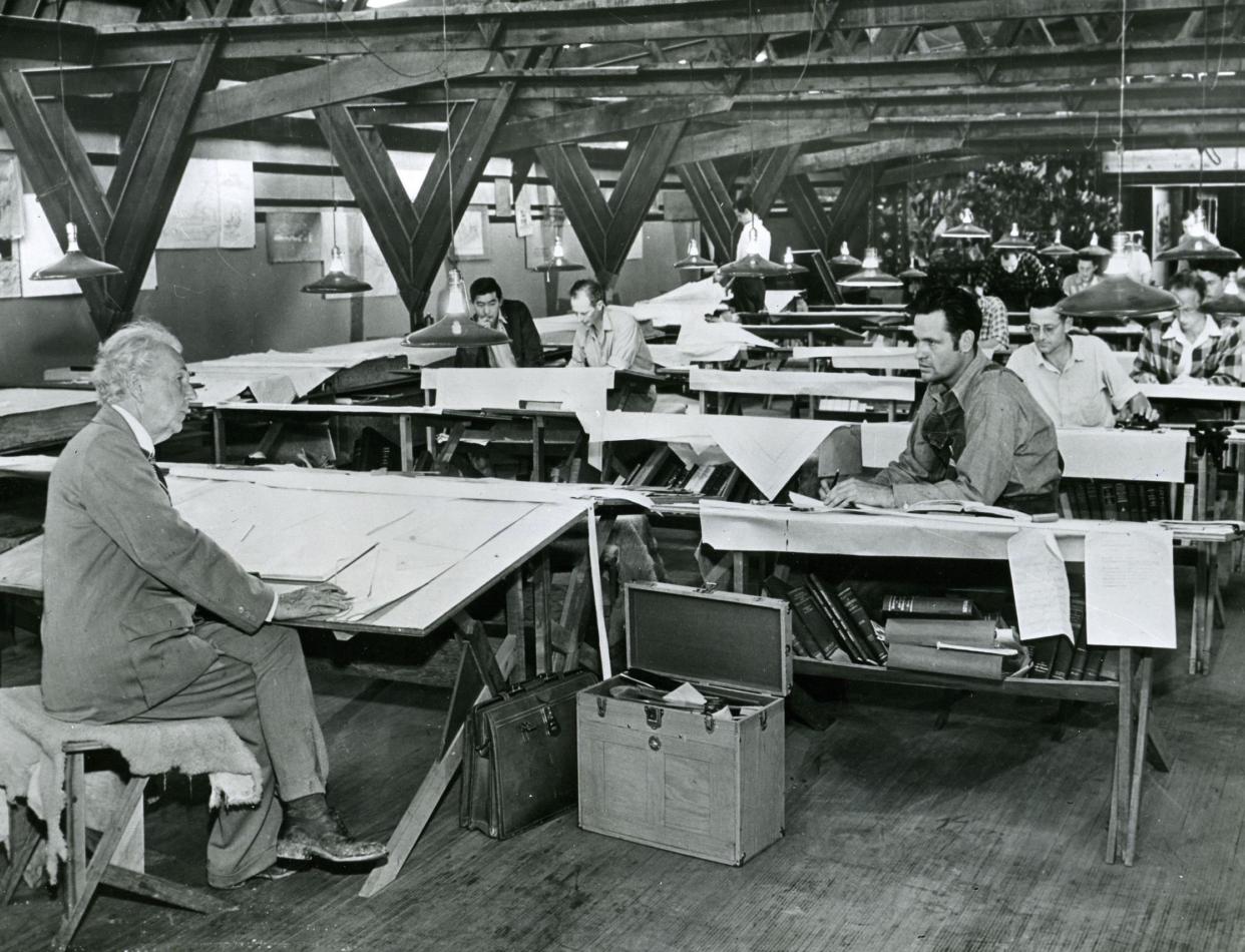 Frank Lloyd Wright discussing plans with one of his apprentices as other students of the 'Taliesin Fellowship' work in the drafting room, 1945: Rex