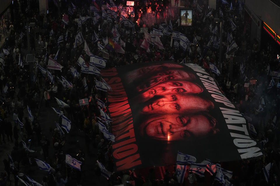 Israelis hold a giant banner depicting Prime Minister Benjamin Netanyahu, center, to protest protest plans by his new government to overhaul the judicial system, in Tel Aviv, Israel, Saturday, Feb. 25, 2023. On Tuesday, Netanyahu's government for the first time advanced the plan by securing a preliminary vote at the Knesset, defying a mass uproar among Israelis and calls for restraint from the United States. (AP Photo/Ariel Schalit)